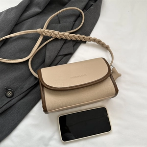 Retro beige crossbody square bag with twisted strap and leather texture next to a phone