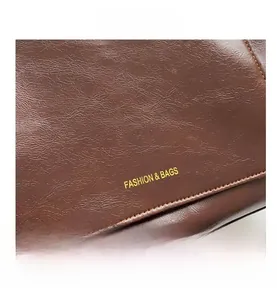 Detailed macro view of dark brown leather tote bag with fine grain and golden fashion text