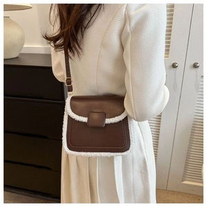 Detailopname van een bruine leren crossbodytas met witte fleece bies gedragen door model