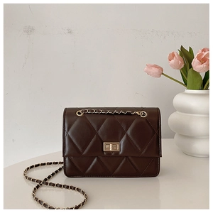 Détail d'un sac en cuir matelassé marron foncé avec fermoir doré et bandoulière chaîne
