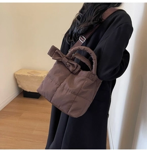 Sac à main matelassé avec nœud marron foncé porté à l'épaule, vue de profil par mannequin