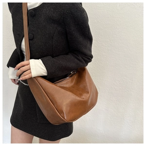 Détail d'un sac hobo en cuir marron vintage avec texture lisse et fermeture éclair