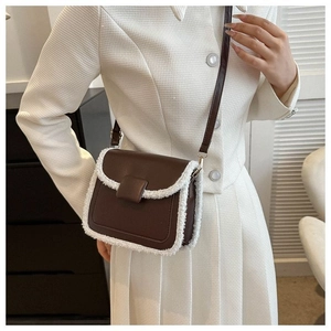 Detail of dark brown crossbody bag with white faux shearling trim and slim strap