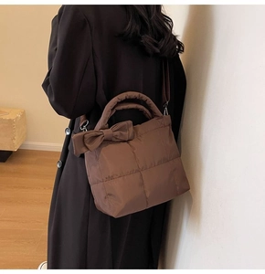 Sac matelassé marron avec détail de nœud et bandoulière porté par un mannequin