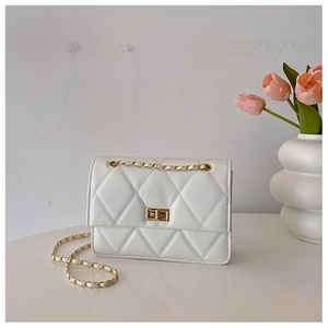 Détail d'un sac bandoulière blanc matelassé avec chaîne dorée et décoration de tulipes