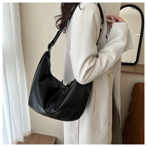 Vue détaillée du sac hobo en cuir noir mat porté avec un trench-coat beige classique