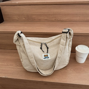 Chic beige corduroy hobo bag with cute bear patch on a wooden staircase display