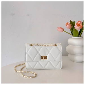 Détail d'un sac bandoulière blanc matelassé avec chaîne dorée et fermoir métallique