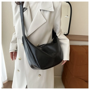 Détail du sac demi-lune en cuir noir montrant la texture lisse et le zip argenté