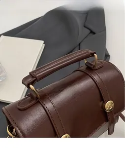 Detailed shot of dark brown vintage leather handbag with gold metal clasp and handle
