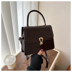 Detail view of a dark brown square bag with a vintage gold teardrop twist lock