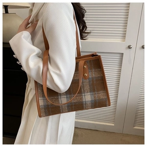 Close-up of vintage plaid tote bag with brown leather trim and metal rivets