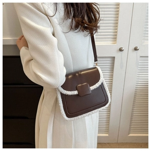 Close-up of brown faux leather crossbody bag with white plush trim on a model