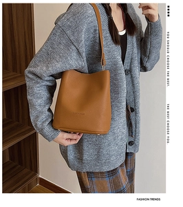 Close-up of caramel leather bucket bag with litchi texture and shoulder strap detail