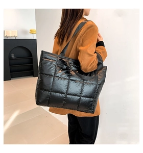 Vista detallada del bolso tote acolchado de nailon negro con acabado brillante y correa ancha