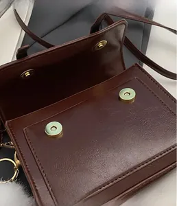 Detailed view of the dark brown leather handbag featuring a golden magnetic closure