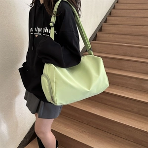 Neon green nylon cylinder crossbody bag with wide strap, shown on model outdoors