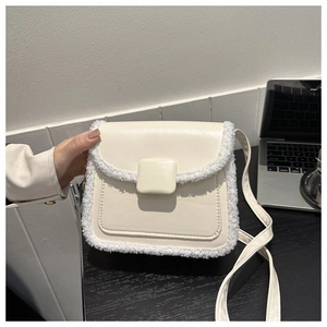 Detail of cream crossbody bag featuring faux shearling trim and smooth leather texture