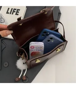 Detailed interior of dark brown leather crossbody bag with magnetic flap and plush charm
