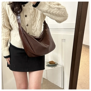 Sac hobo croissant marron brillant porté à l'épaule lors d'un selfie miroir
