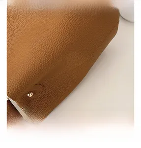 Close-up of brown litchi pattern leather texture with gold metal rivet detailing