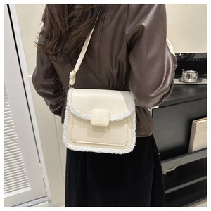 Detail of cream crossbody bag with faux fur trim on a model wearing a brown leather jacket