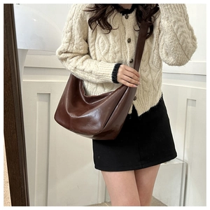 Sac hobo vintage en cuir ciré marron porté en bandoulière sur une épaule par un mannequin