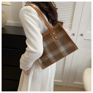 Macro shot of brown plaid tweed tote bag with leather trim and gold rivet details