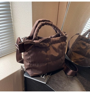 Détail d'un sac à main matelassé marron foncé avec un grand nœud et une large bandoulière