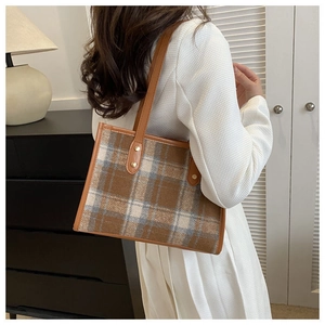 Detail of vintage plaid tote bag featuring brown leather straps and gold rivet accents