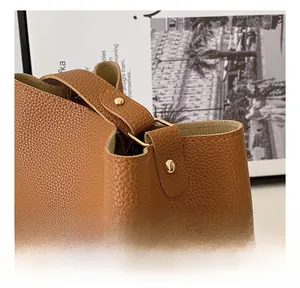 Detailed macro shot of brown pebble grain leather bucket bag with gold metal rivet hardware