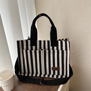 Sac fourre-tout en toile rayée avec poignées noires et bandoulière réglable sur bois