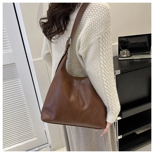 Detail of vintage brown leather tote bag showing soft texture and metal buckle on shoulder