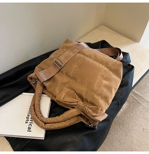 Détail d'un sac cabas en duvet matelassé marron avec nœud et bandoulière réglable