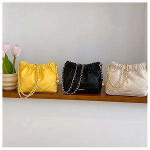 Quilted bucket bags in black, yellow, and beige with chain straps and gold ball charms