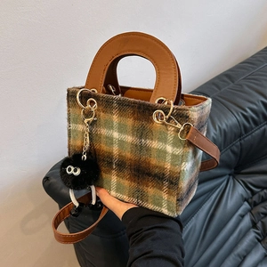 Retro green wool plaid tote bag with brown leather handles and plush black charm