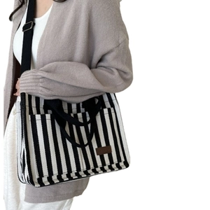 Grand sac fourre-tout en toile rayée avec bandoulières noires et patch de mode sur modèle