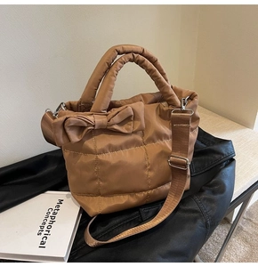 Détail d'un sac matelassé marron avec nœud décoratif et bandoulière en nylon réglable