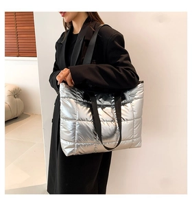 Detalle del bolso tote plateado acolchado con acabado metálico y asas negras