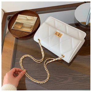 Détail du sac à bandoulière matelassé blanc avec chaîne dorée et fermoir pivotant en métal