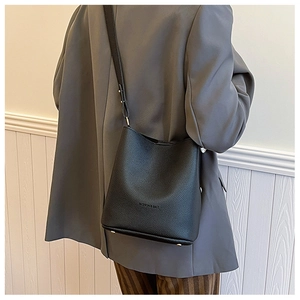 Detail of black lychee grain leather bucket bag featuring gold protective base studs