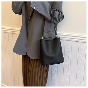 Close-up of black lychee grain bucket bag featuring a bottom protective metal stud detail