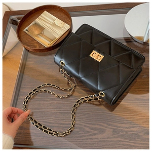 Détail d'un sac bandoulière matelassé noir avec chaîne dorée et fermoir rotatif
