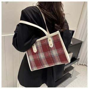 Detail of red and grey plaid wool tote bag with white leather trim and gold rivets