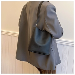 Close-up of black lychee grain leather bucket bag featuring gold feet and fashion embossing