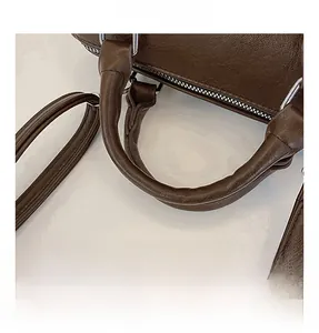 Detail shot of vintage dark brown leather boston bag showing round handle and silver hardware