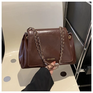 Detail of dark brown faux leather tote with golden chain strap and fashion text