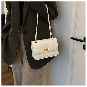 Mannequin portant un sac matelassé beige avec bandoulière chaîne et fermoir doré chic