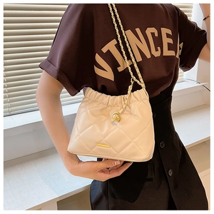 Detail of quilted leather bucket bag with gold chain strap and metal ball charm decoration
