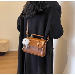 Detail of vintage brown patent leather mini bag with plush monster charm and top handle